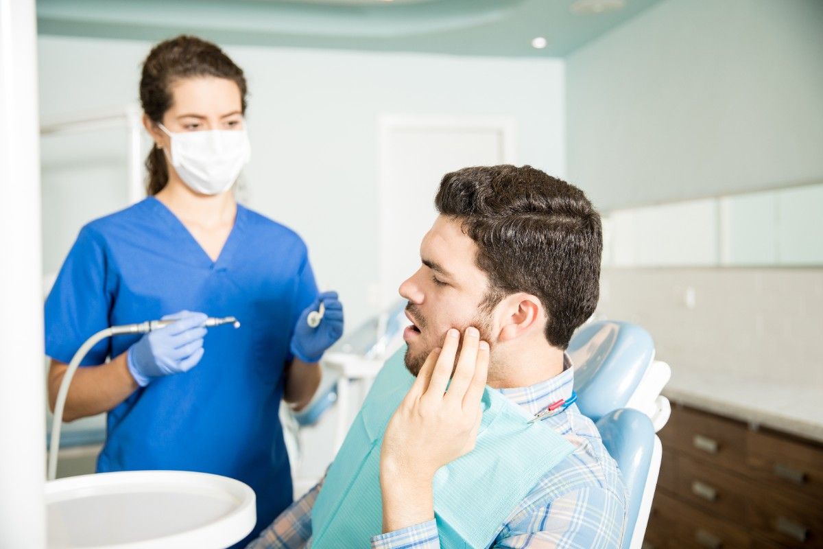 mid-adult-man-suffering-from-toothache-while-looking-dentist-with-tools-clinic (1)